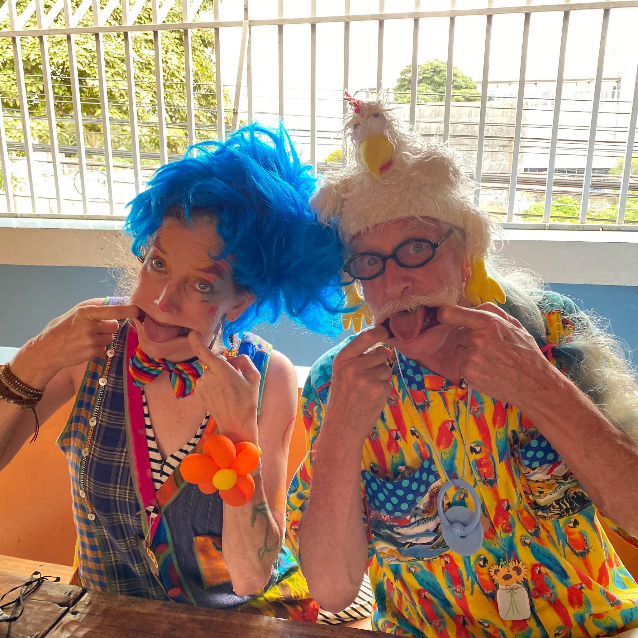 Two clowns making playful faces in bright costumes