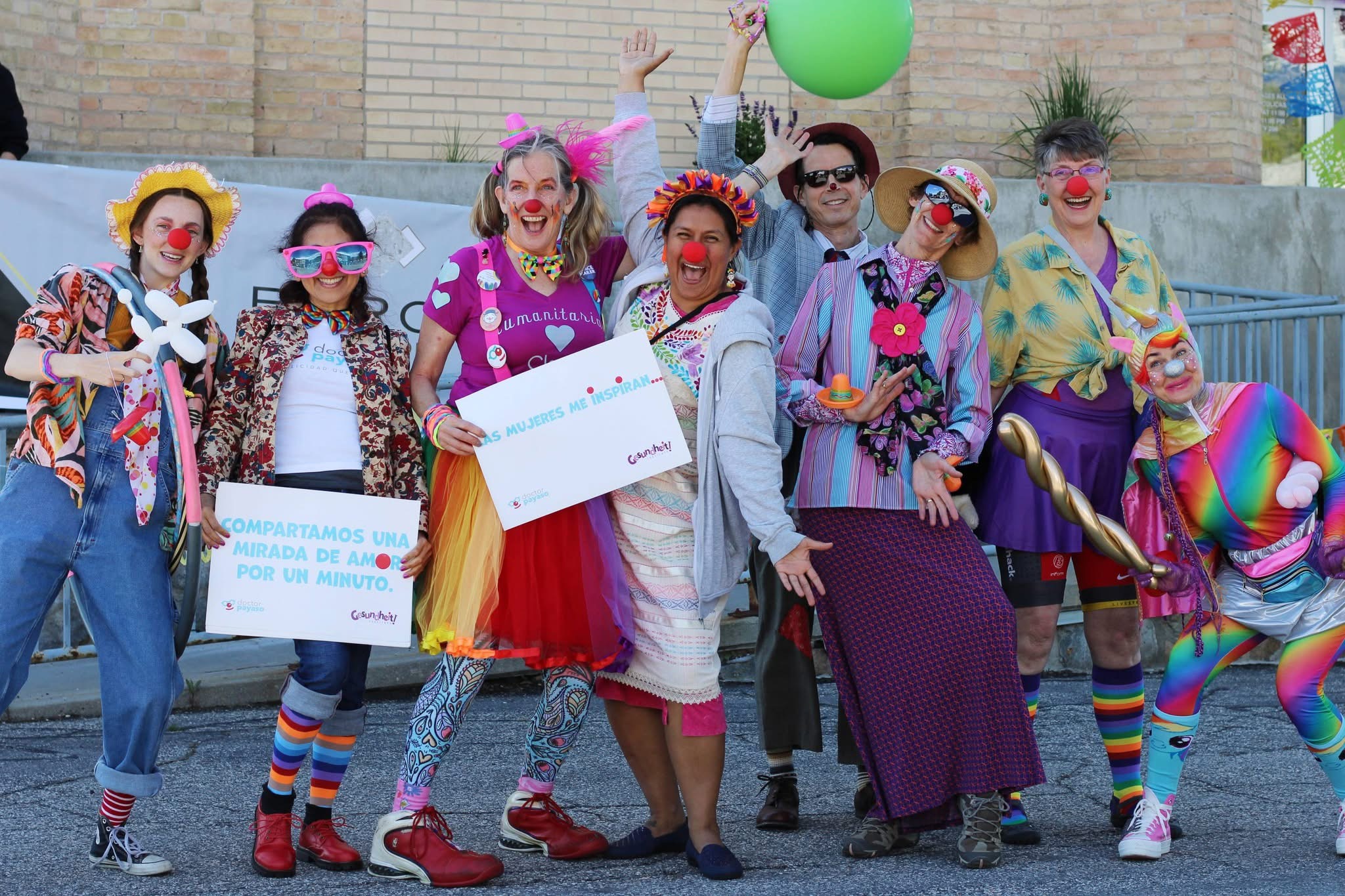 A joyful group of clowns posing together in colorful costumes and red noses
